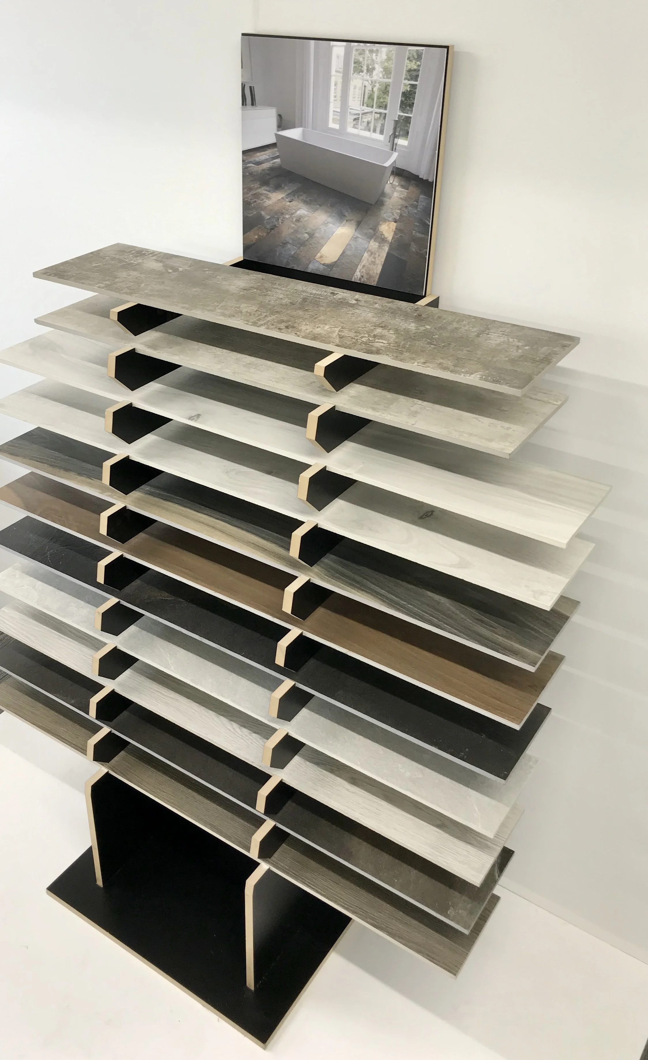 Display stand with various wood and stone flooring samples and a picture of a bathtub on a textured floor.