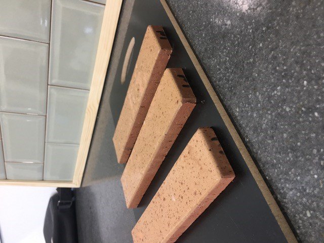 Three rectangular sponges on a gray countertop with a tiled backsplash in the background.