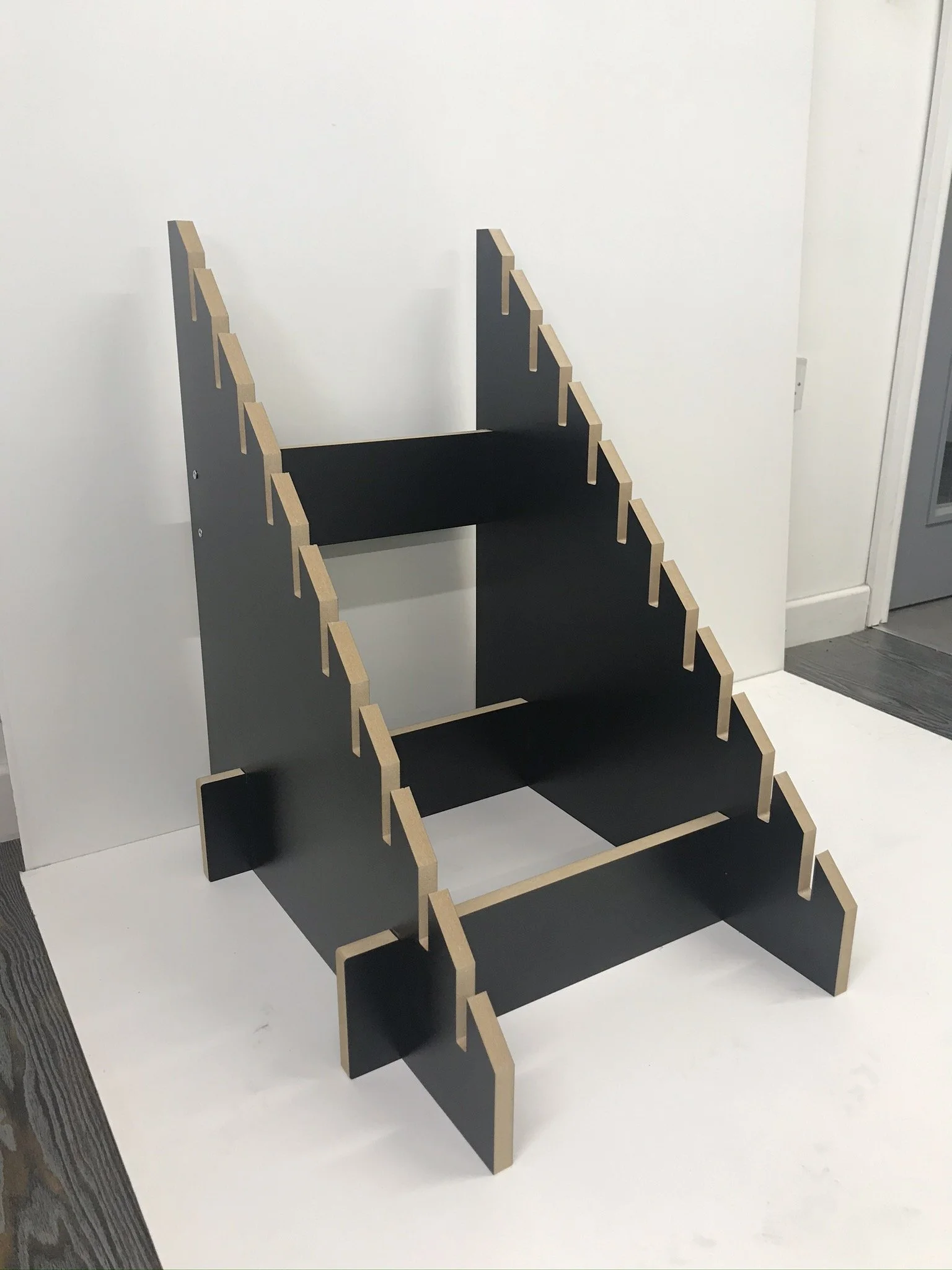 A black wooden modular shelf with peg-like sides on a white background.