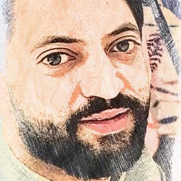 Close-up of a man's face with dark hair, beard, and mustache, looking at the camera.