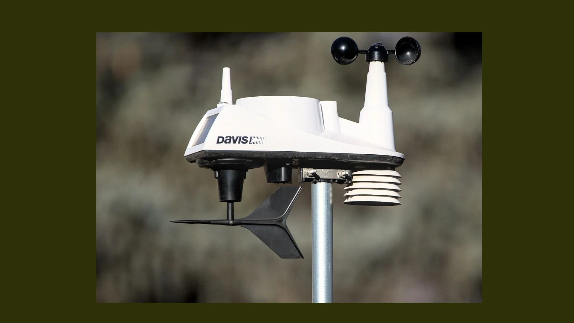 Automated weather station with sensors, including anemometer, wind vane, and other meteorological instruments mounted on a pole.