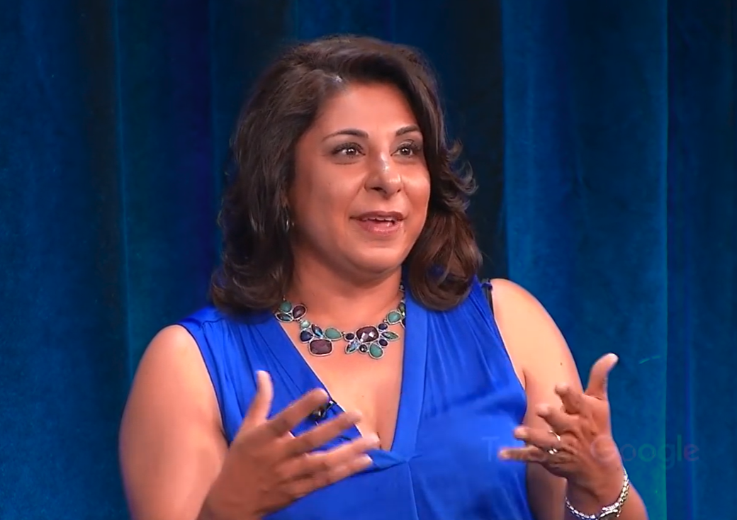 woman with dark hair and bright blue top speaking