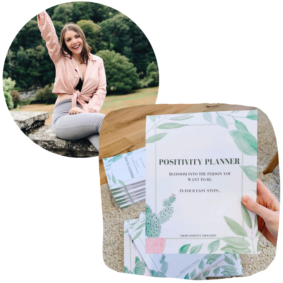 A woman sitting outdoors on a stone ledge, smiling and raising her arm, with a green natural background, and a table in the foreground held with a booklet titled 'Positivity Planner' with a cactus illustration.