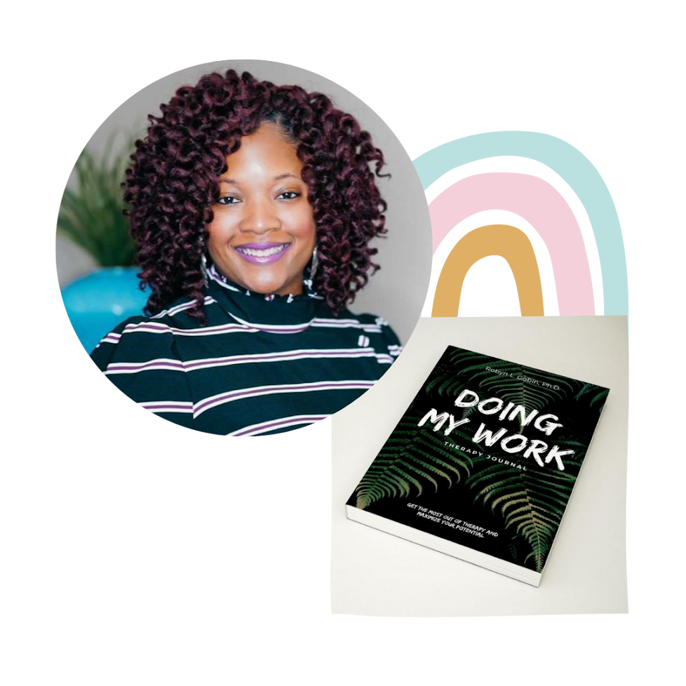 A smiling woman with curly hair and purple lipstick, wearing a black and white striped turtleneck, sitting at a desk with a book titled 'Doing My Work: The Therapy Journal' in front of her.