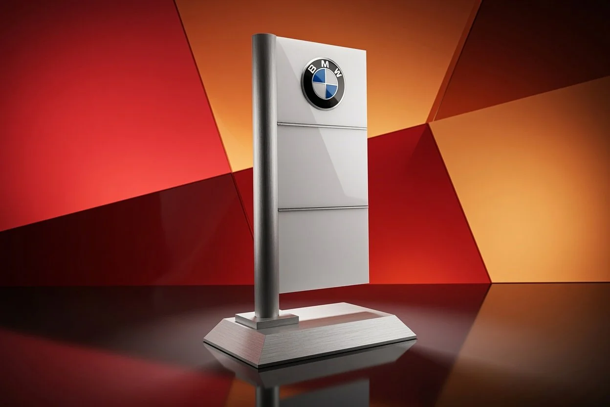 A custom corporate award of the BMW logo on a metallic standing display with a geometric red and orange background.