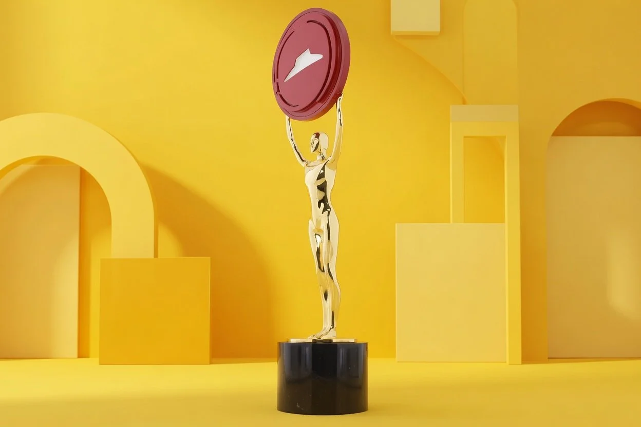 Golden statue of a figure holding a red circular medal with the Pizza Hut logo above her head, situated on a black pedestal against a yellow background with abstract yellow shapes.