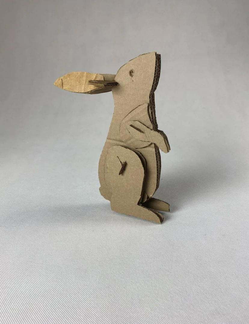 A cardboard cutout of a bunny, featuring minimalist details and a plain background.