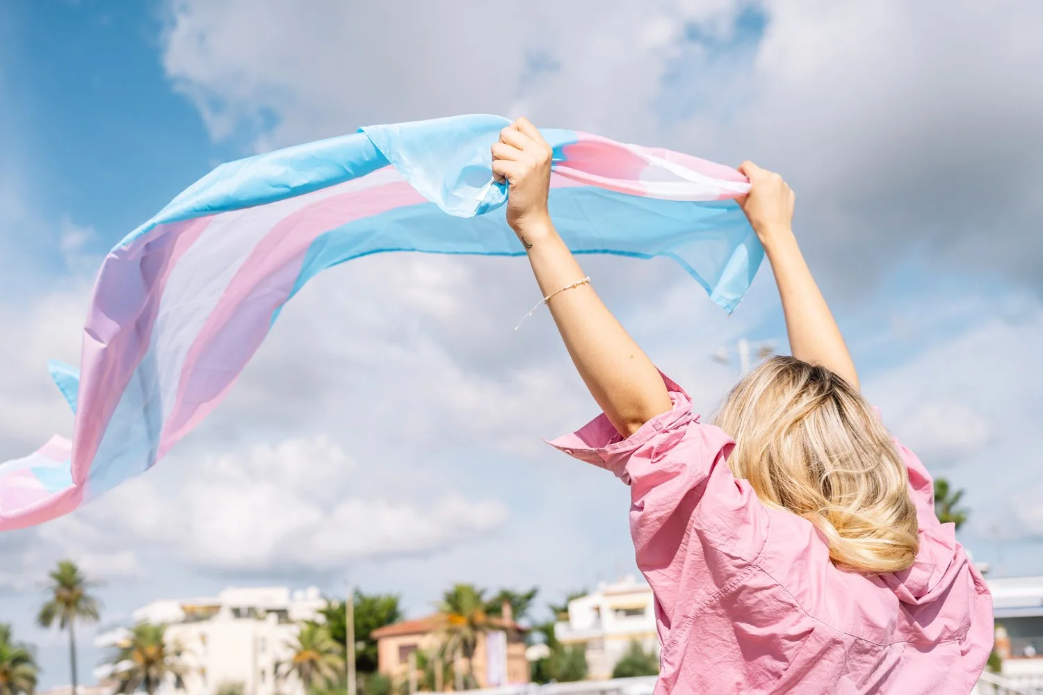 Person holding a transgender pride flag outdoors