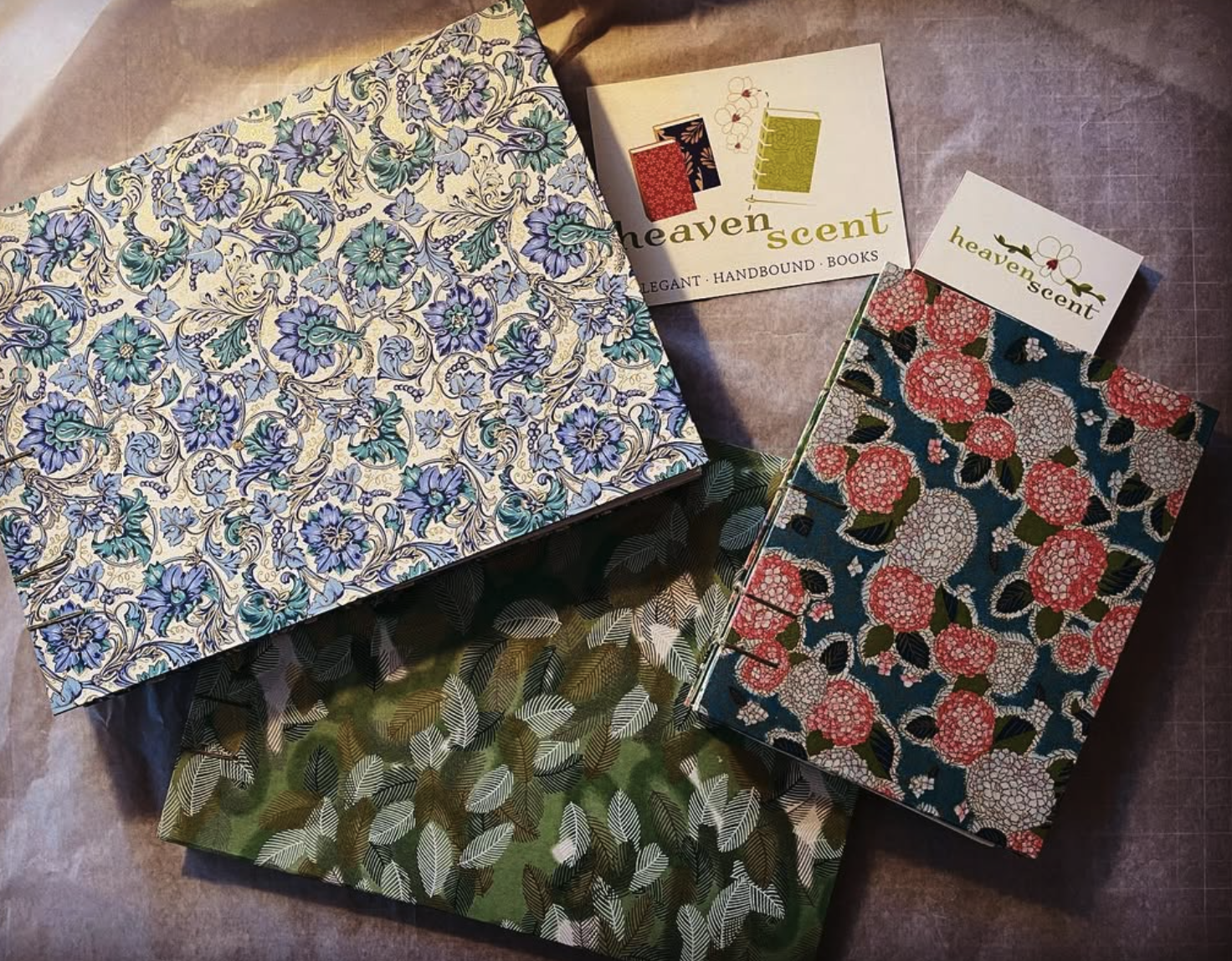 Assorted decorative notebooks and stationery with floral and leafy patterns on a table.