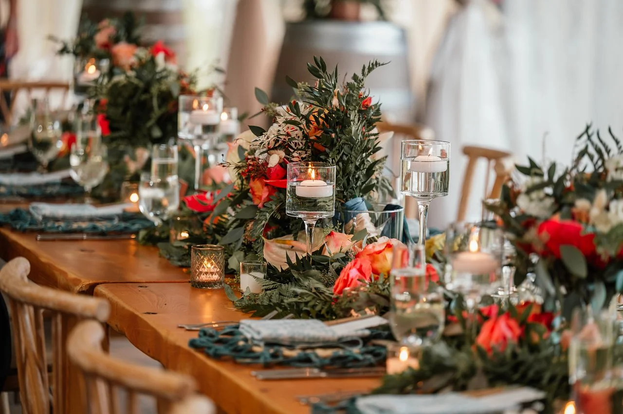 Decorated dining table with floral centerpiece, candles, glassware, and napkins for a formal event.