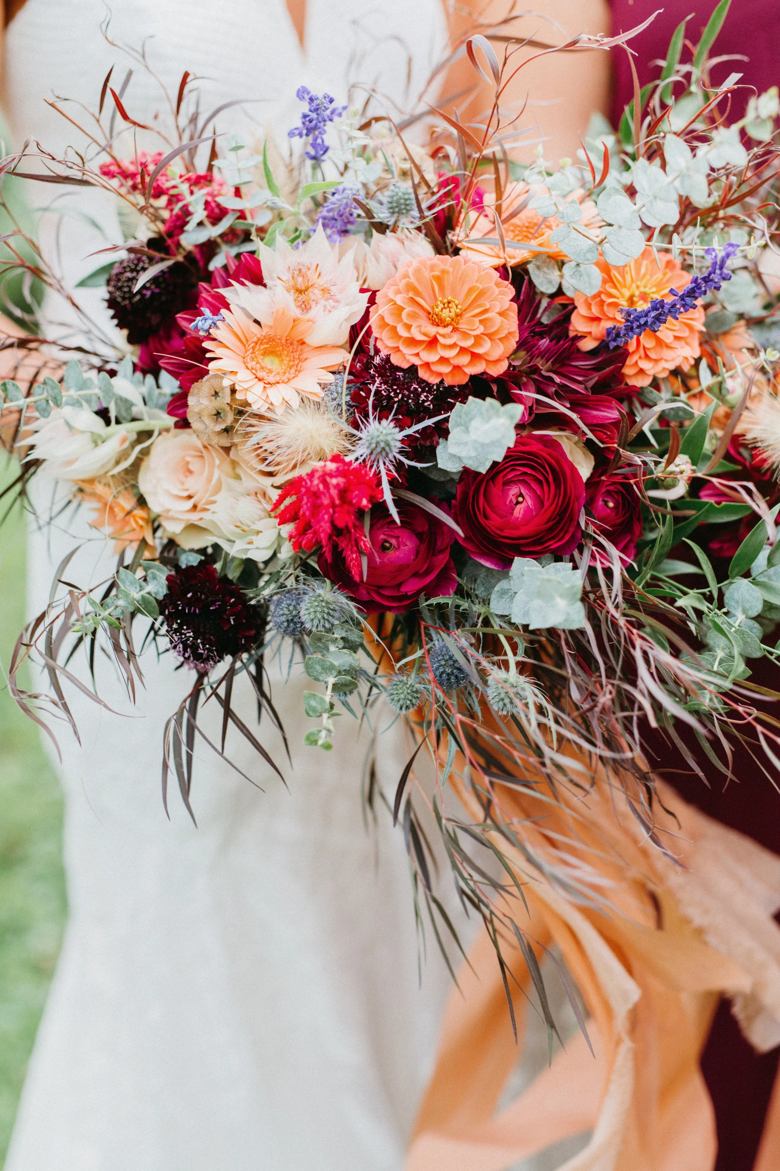 Colorful bouquet of various flowers including orange dahlias, pink roses, purple lavender, and greenery.
