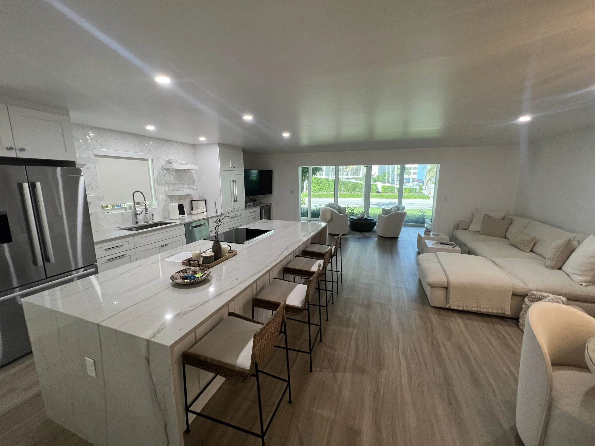 Open-concept kitchen and living room featuring a quartz island, custom cabinetry and hardwood floors in southwest florida