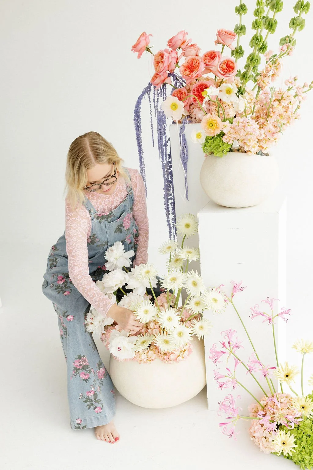 A woman arranging white and pink flowers in a garden setting.