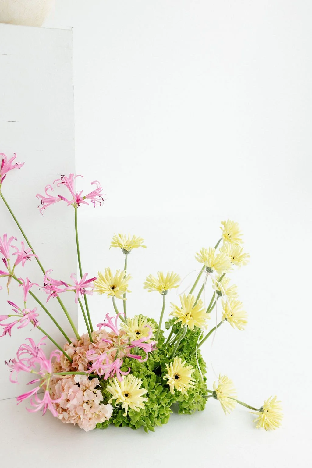 Arrangement of pink, yellow, and green flowers against a plain white background.