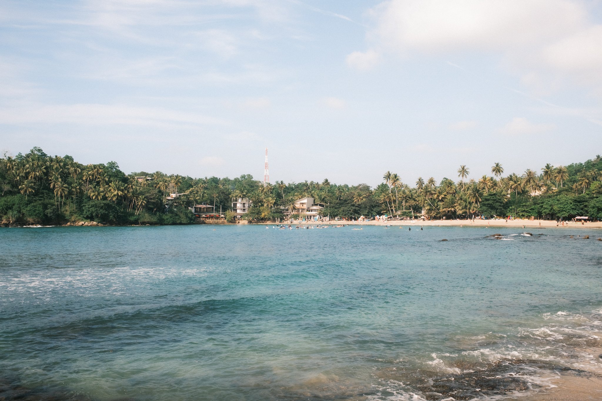 This picture shows a beach in Hiriketiya Sri Lanka with wonderful blue water and surrounded by palm trees