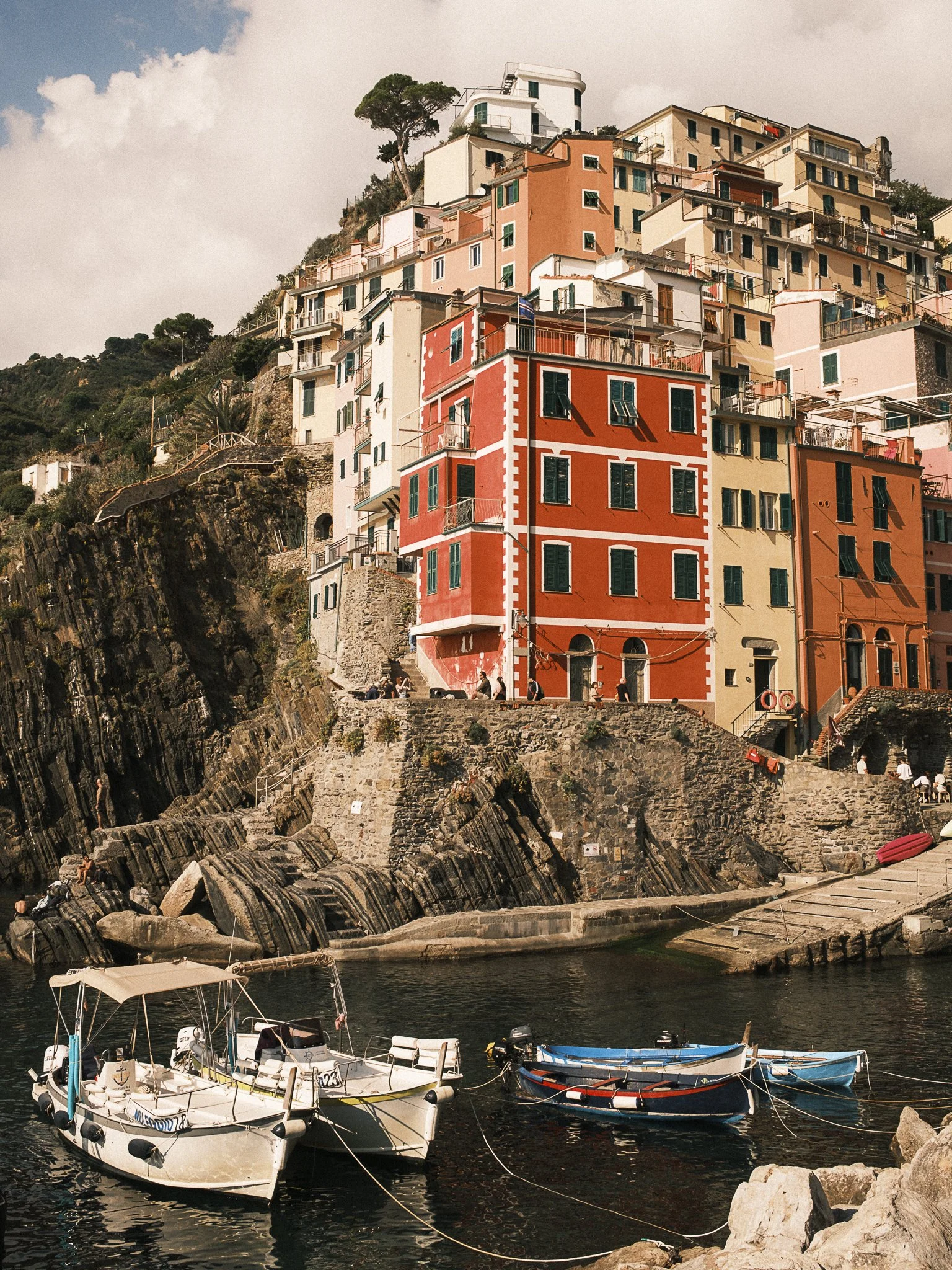 Colorful cluster of buildings on a hillside overlooking the water with boats docked in the foreground.