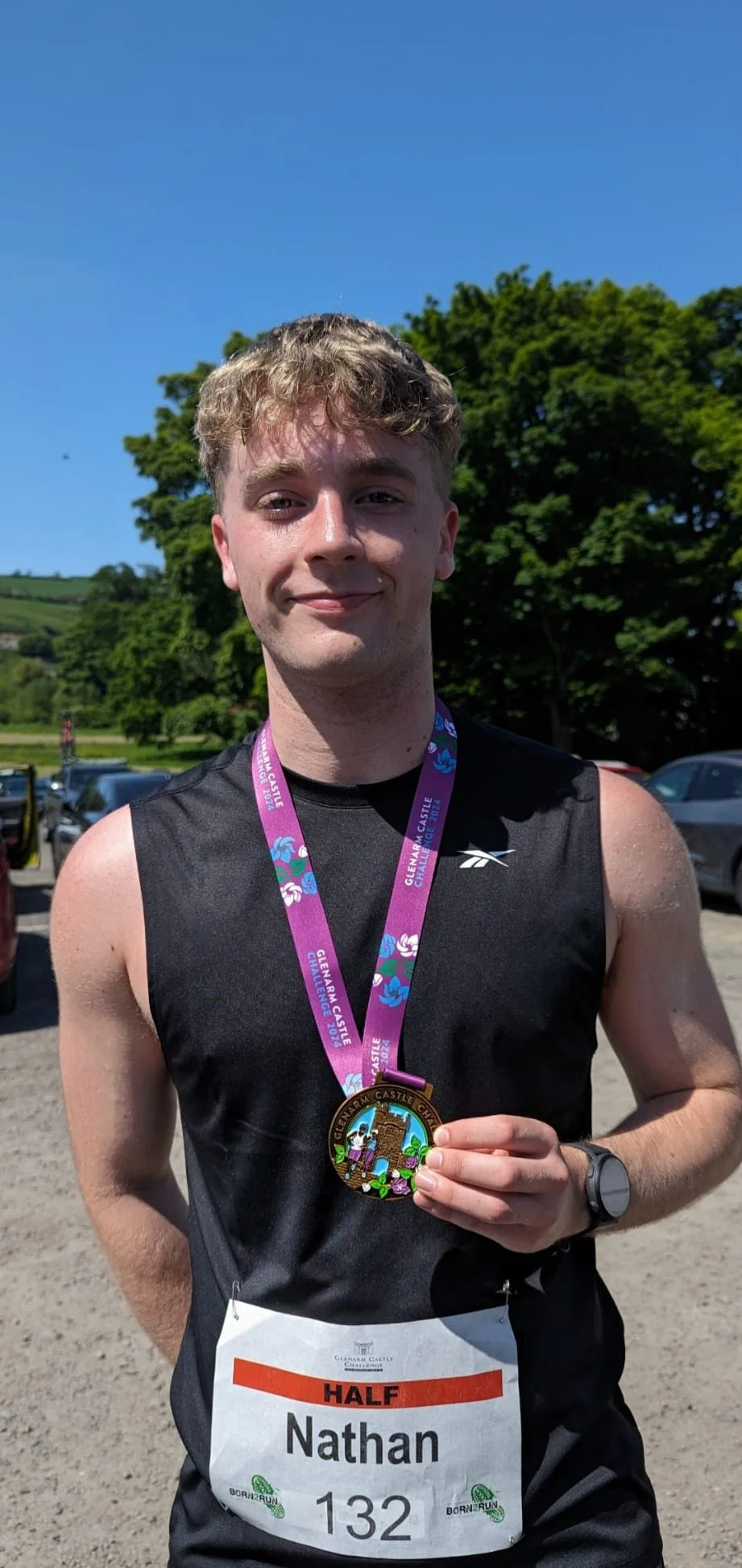 Nathan Maguire holding a medal after completing the Glenarm Castle Challenge.