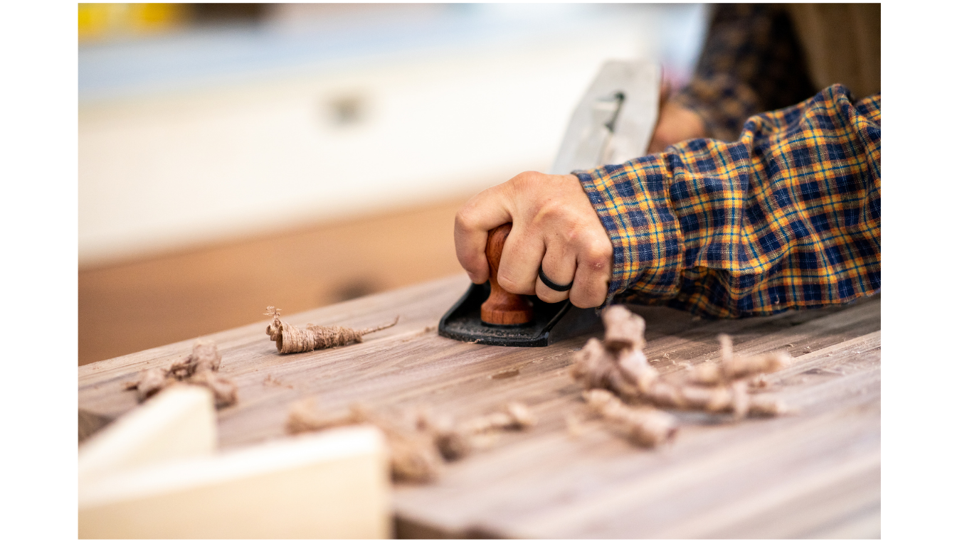 Carpenter using a hand planer on a wood project.