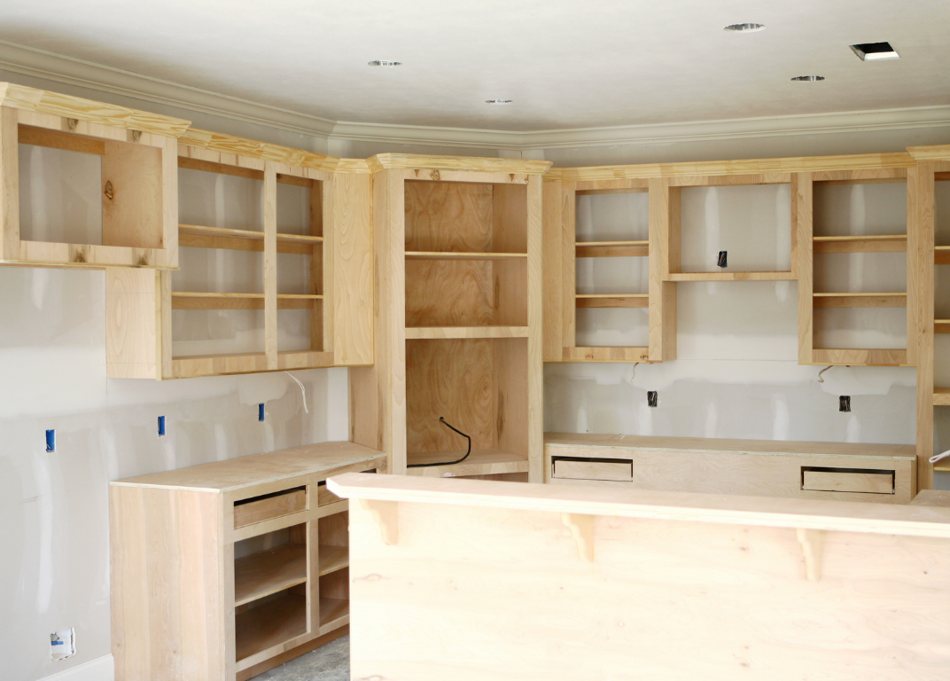 unfinished custom built-in wooden cabinets and shelves in a kitchen or bar area under construction.