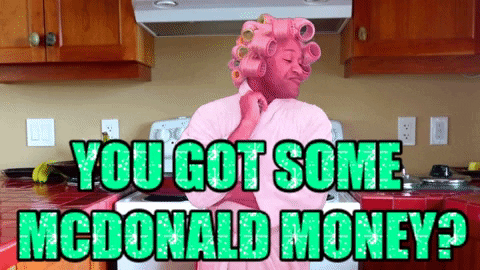 A person dressed as a pink figure with curlers in their hair in a kitchen, with the text 'YOU GOT SOME MCDONALD MONEY?' in bright green and teal.