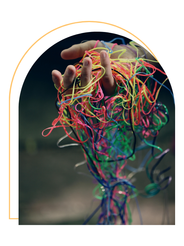 A hand holding a tangled mess of colorful rubber bands.