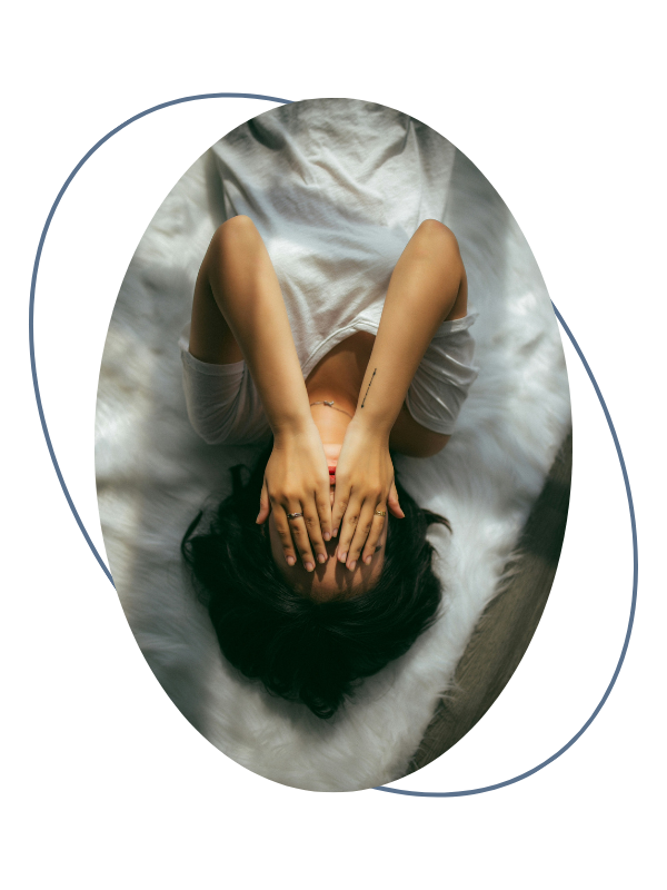 A woman lying on a bed with her hands covering her face