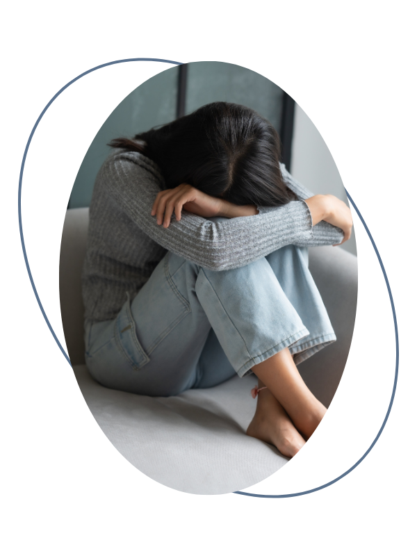 woman sitting on a couch with her knees pulled to her chest, head resting on her arms, appearing upset or upset in a sad or distressed state