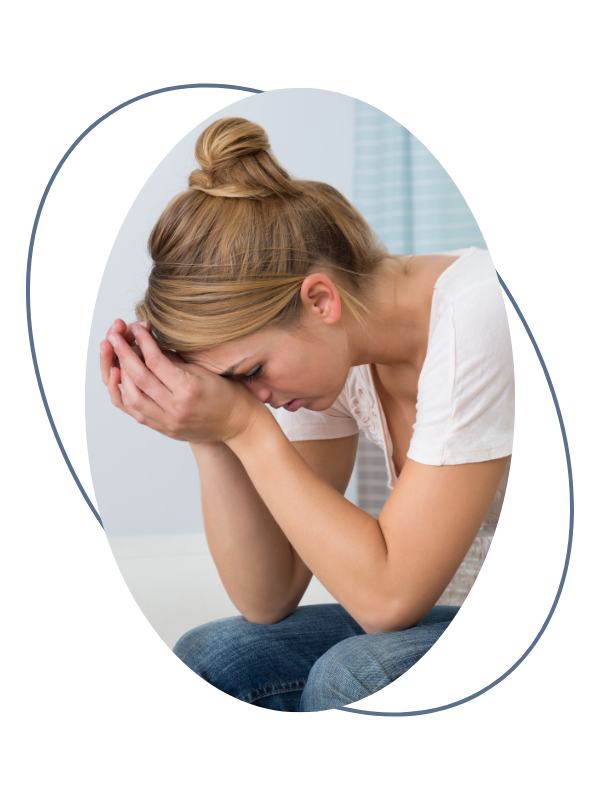 A woman sitting with her head bowed and hands covering her face, appearing distressed or upset.