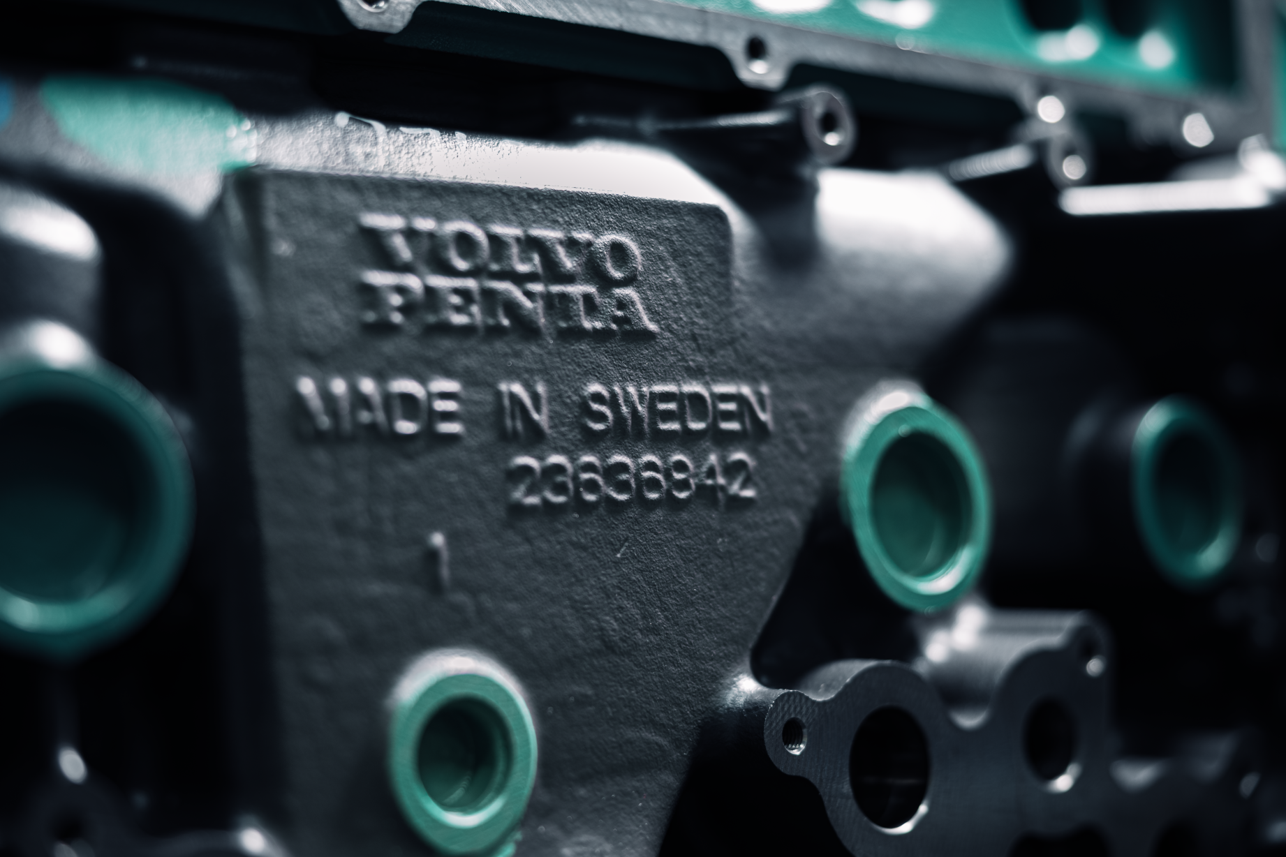 Close-up of a mechanical component with the text 'TOHYO PENTA' and 'MADE IN SWEDEN' embossed on its surface, featuring several green-tinted circular openings around it.