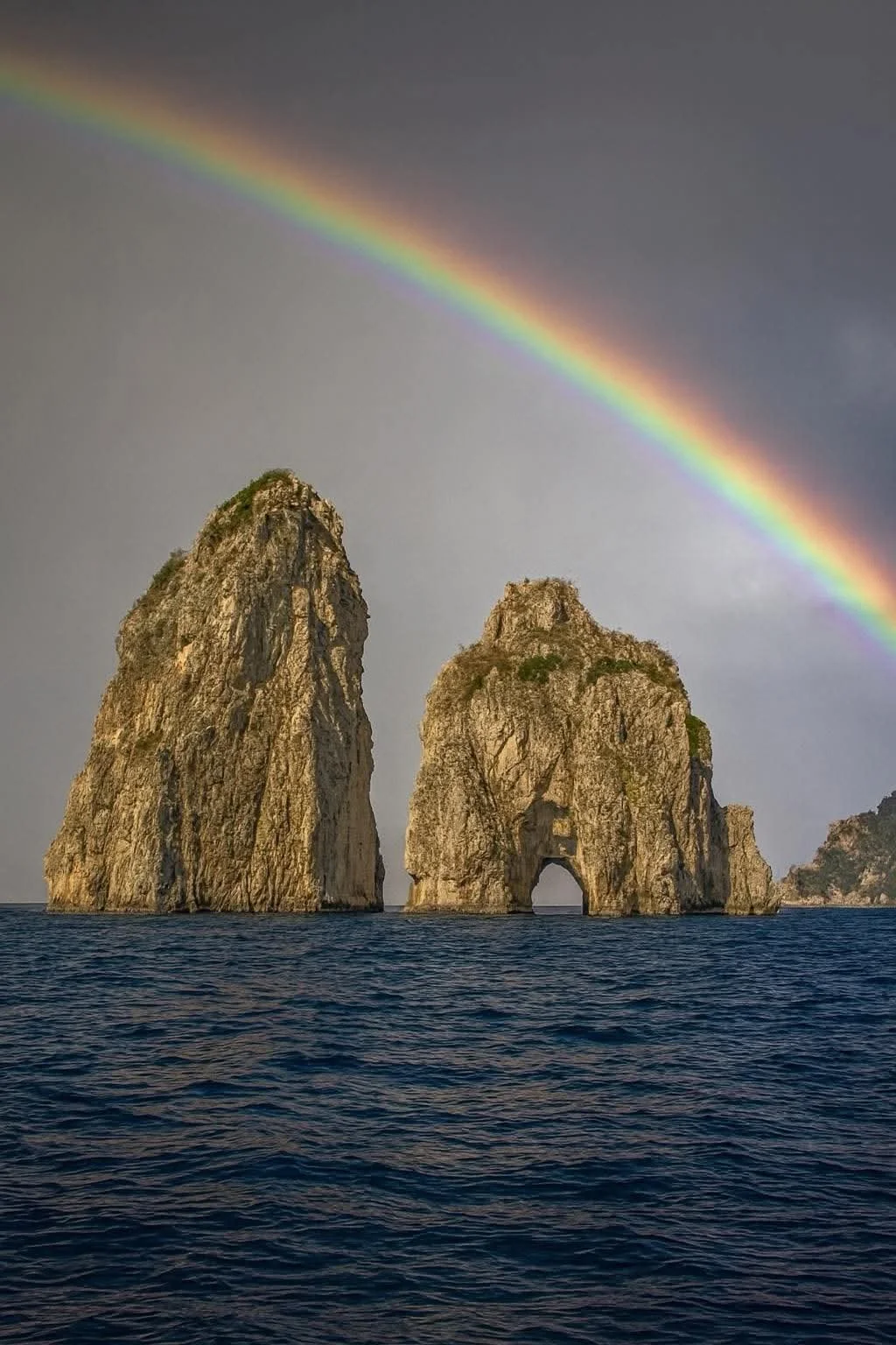Zwei Felsen im Meer mit Regenbogen am Himmel