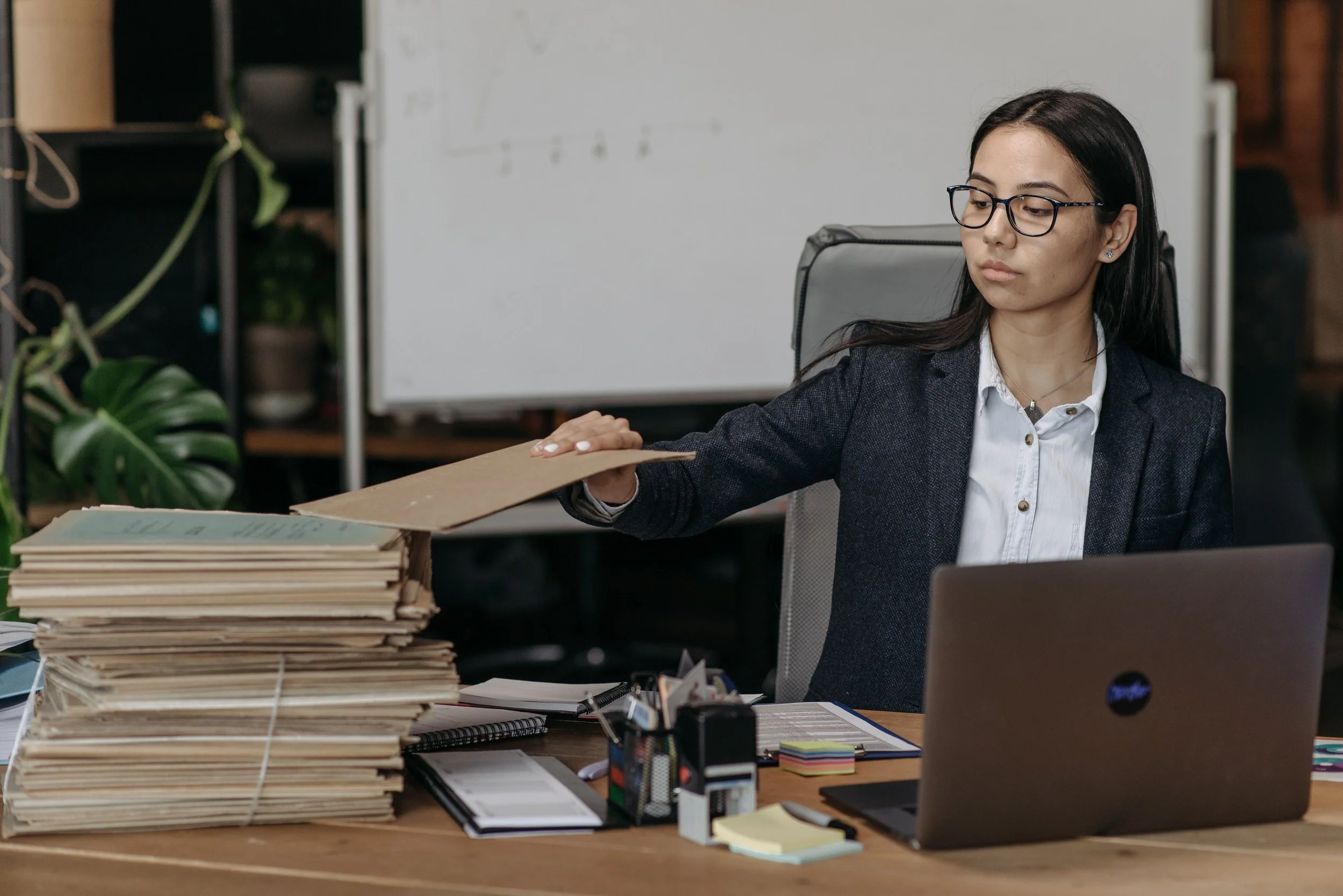 Woman working at her desk in front of her laptop with a pile of documents