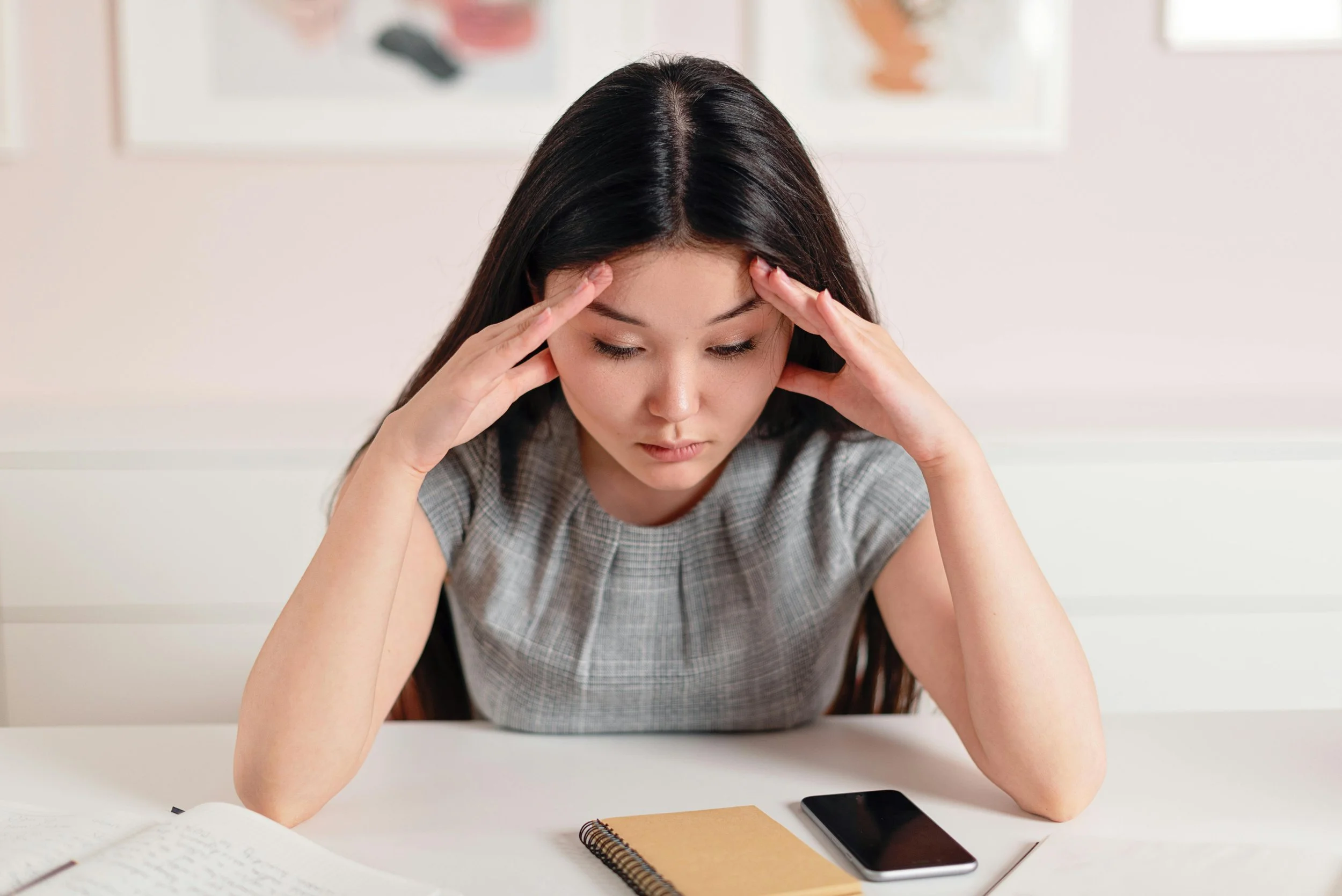 Woman feeling overwhelmed while reviewing notes and responsibilities before creating a clear plan.