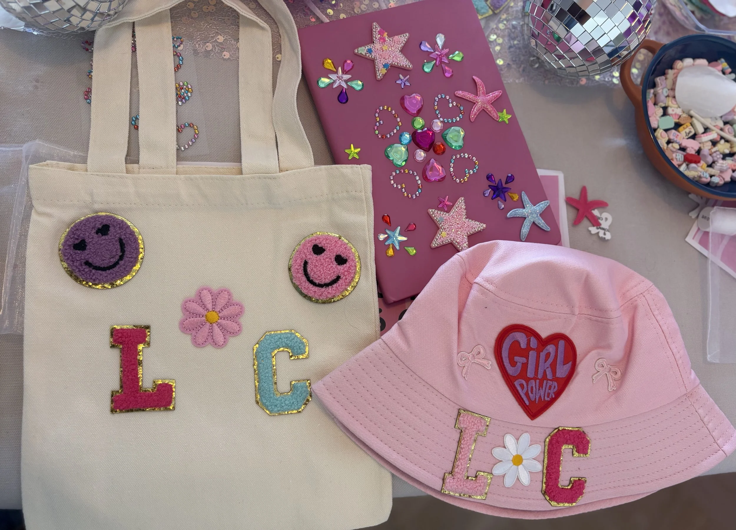 A collection of colorful decorative patches, stickers, and accessories with a love and star theme on a table, including smiley face patches, the word love spelled out with letter patches, and various star and heart shaped embellishments.