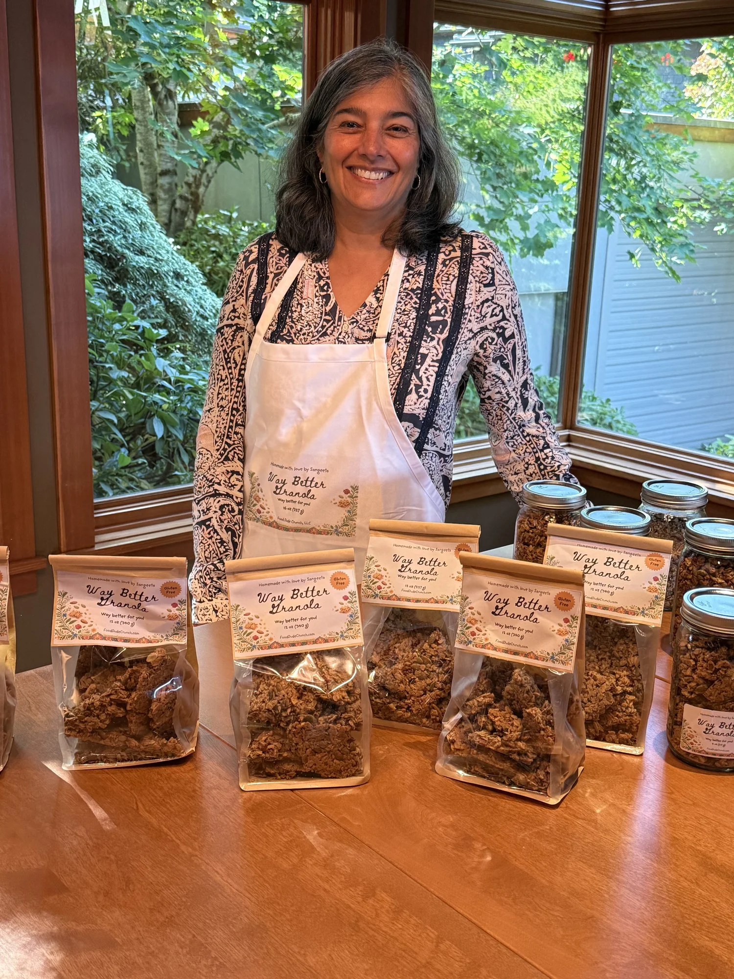 Sangeeta in her kitchen with bags of granola