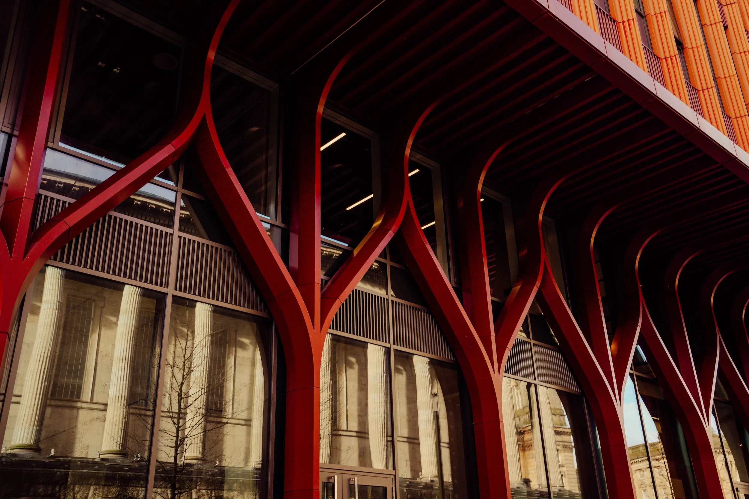 Modern building with unique red structural design and large glass windows.