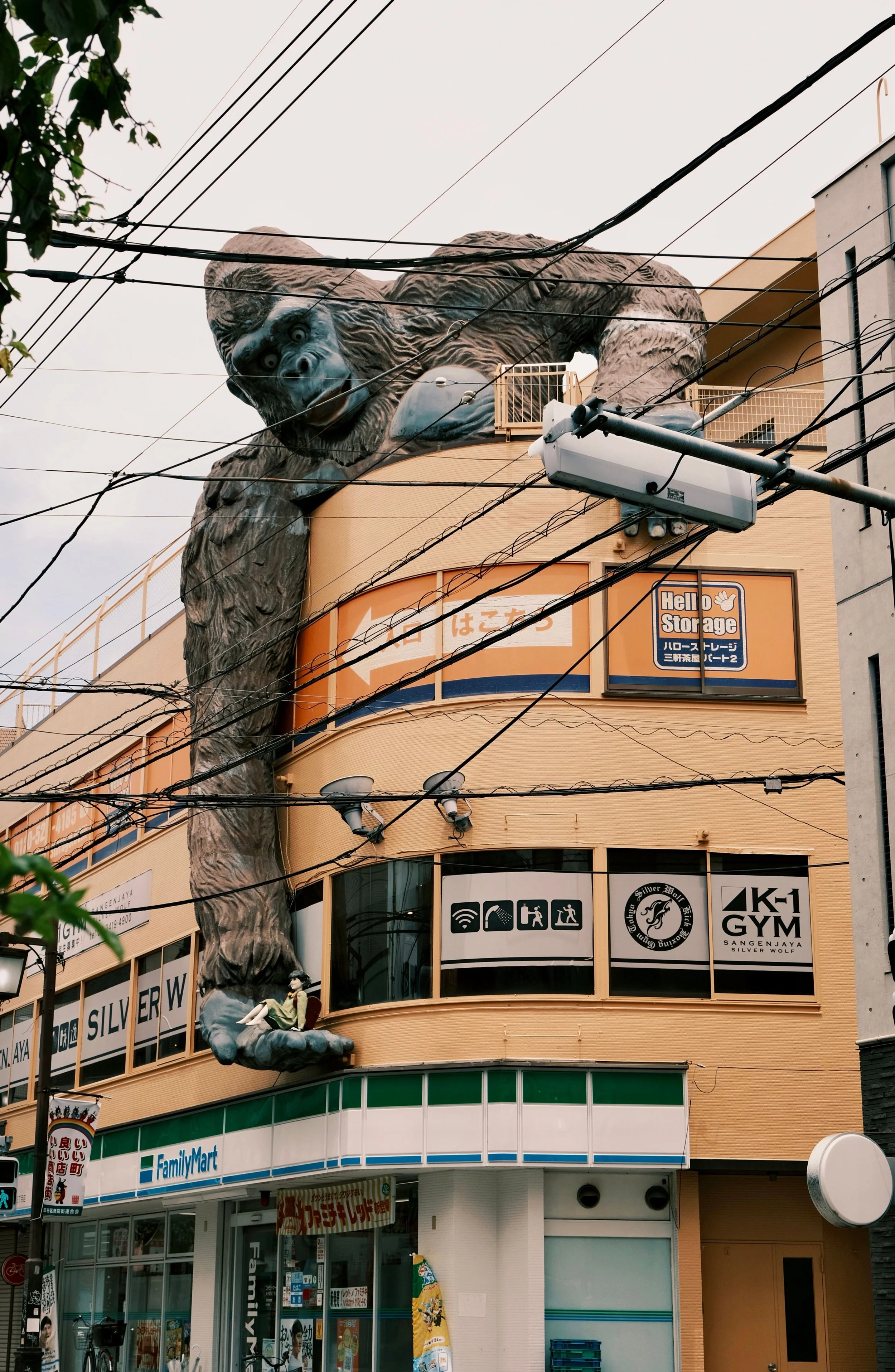 Large gorilla sculpture climbing on a building facade, with a woman sitting on its hand.