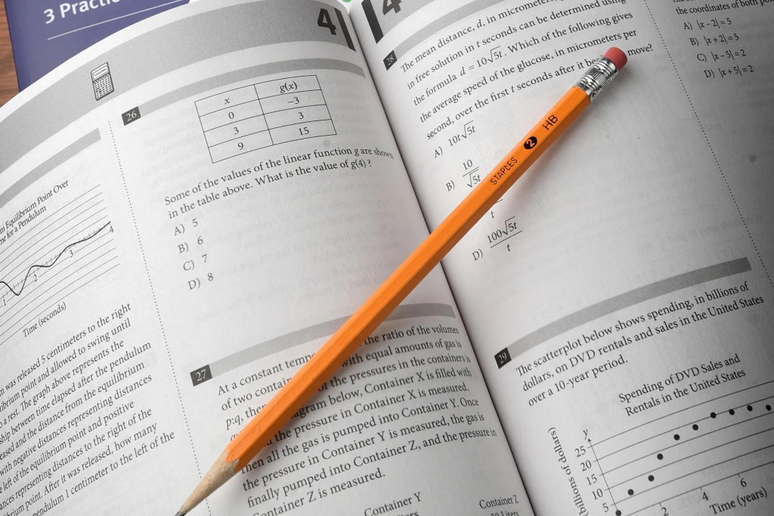 An open math textbook on a wooden surface with a yellow and red STAEDTLER pencil resting on it.