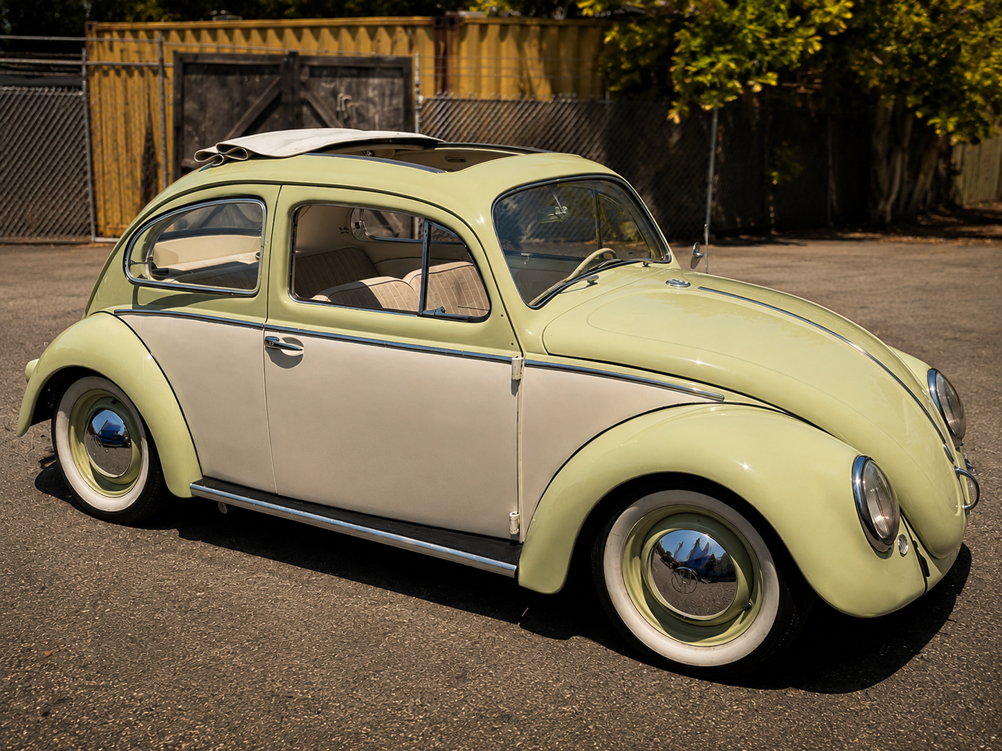 Restored yellow and cream vintage Volkswagen Beetle parked outside the BenBuilt Customs shop in California.