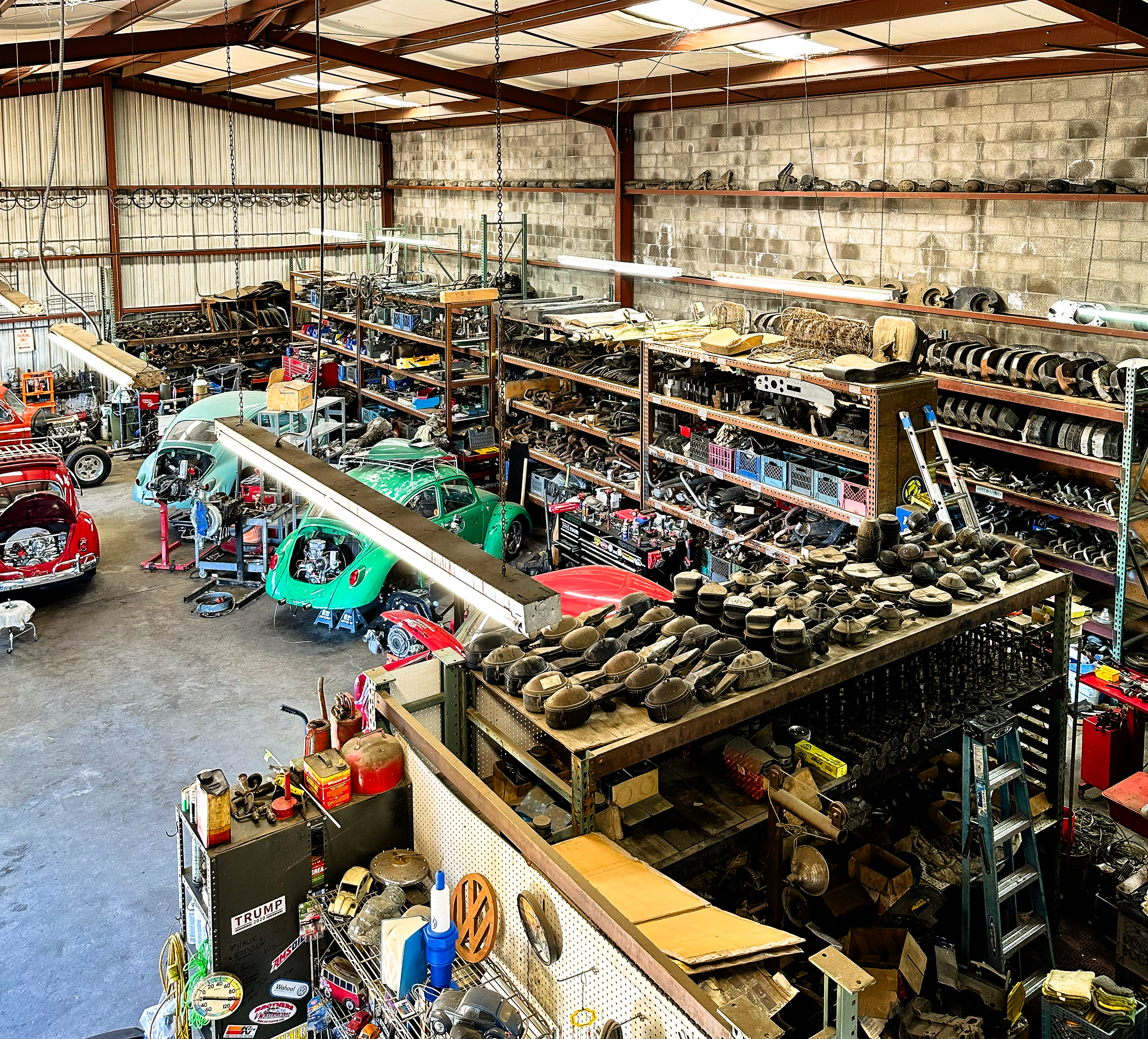 A large indoor warehouse filled with vintage car parts, tools, and accessories neatly stored on shelves and racks.