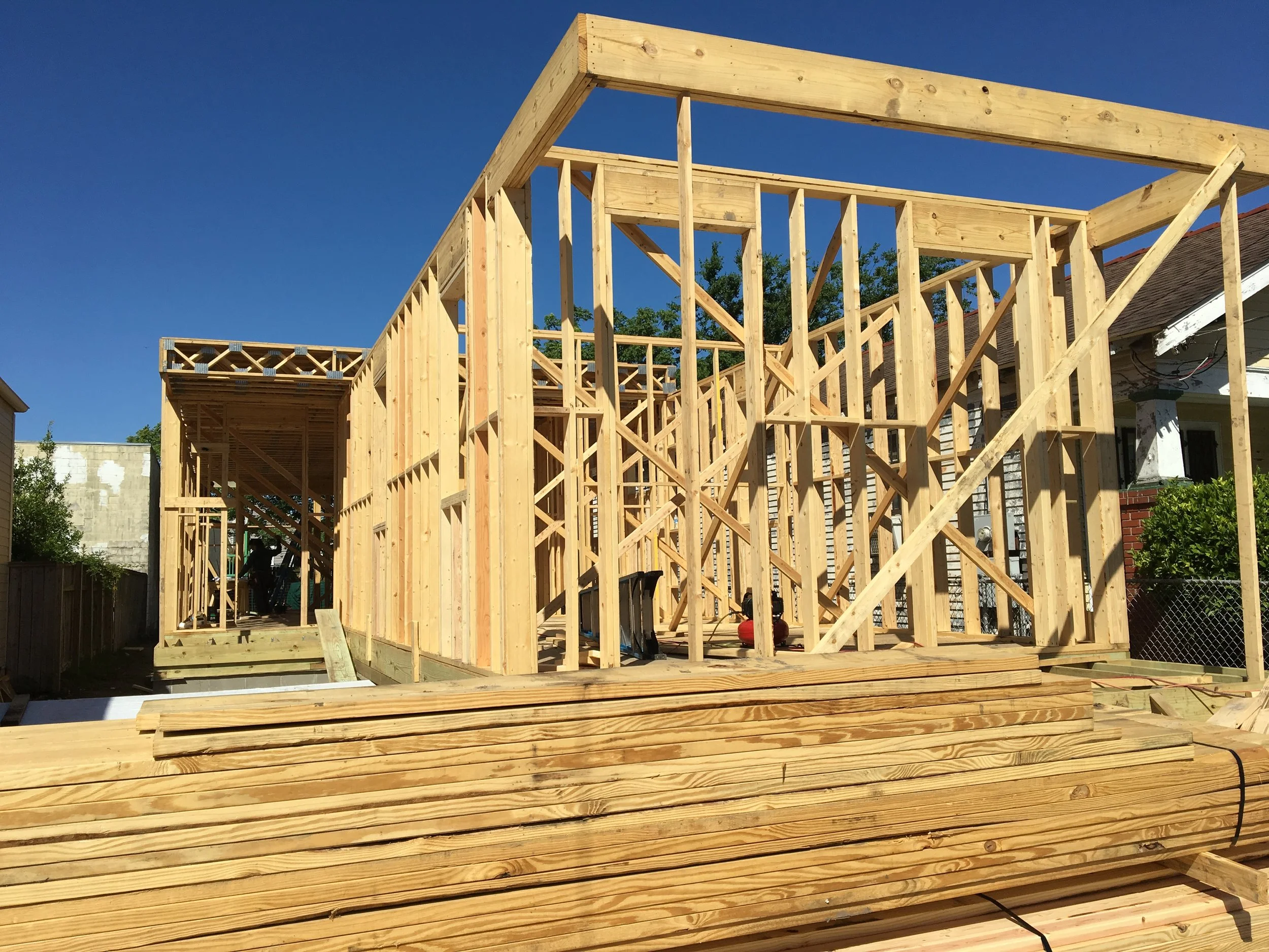 Wooden framing for a house under construction with a clear blue sky in the background.
