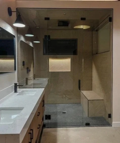 A modern bathroom with a double vanity, two sinks, mirrors, and a glass-enclosed shower area.