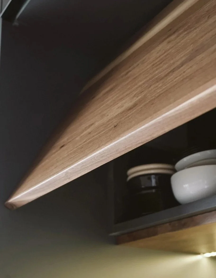 Close-up of a wooden shelf with white and black bowls underneath it.