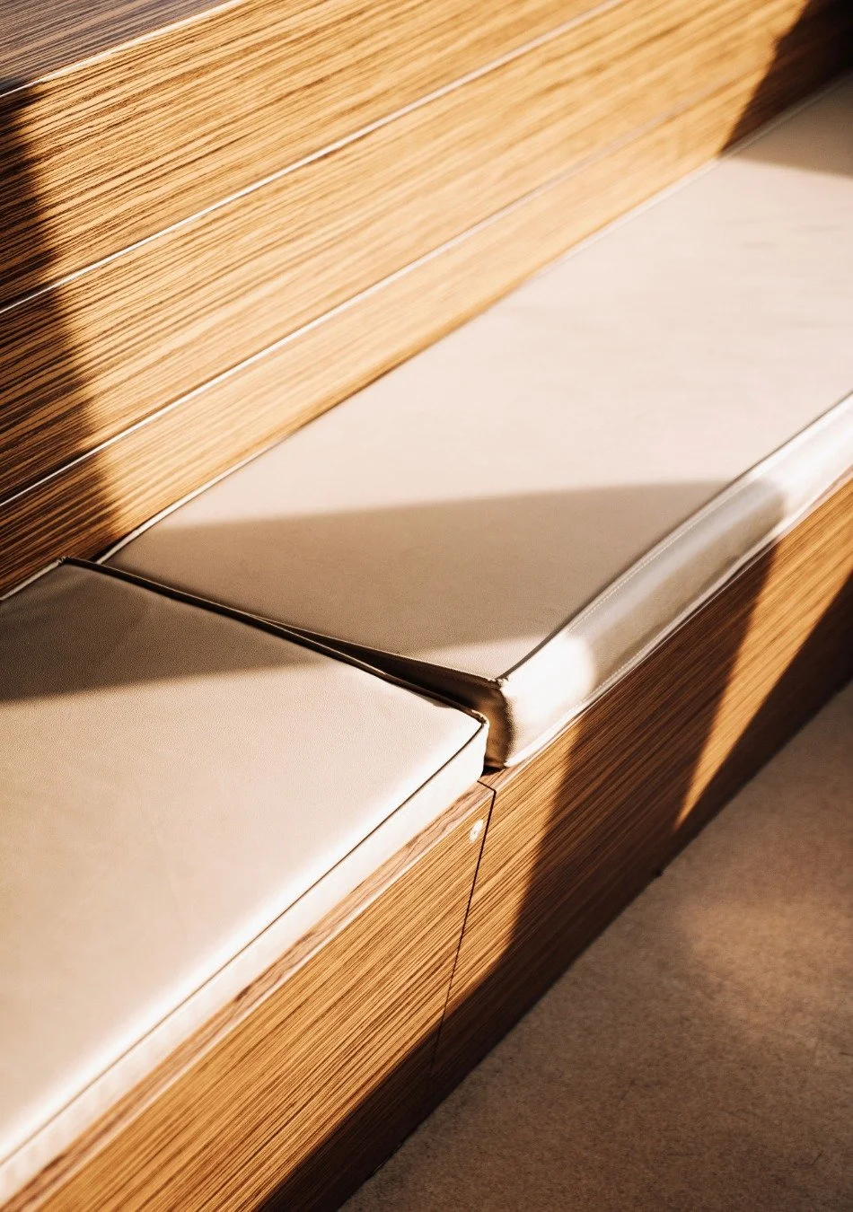 Close-up of a wooden cabinet with a metallic ledge, showing shadows and part of the cabinet's edge.