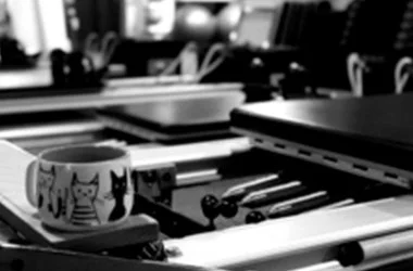Office desk with stationery items, a mug with cat illustrations, and various office supplies in black and white.