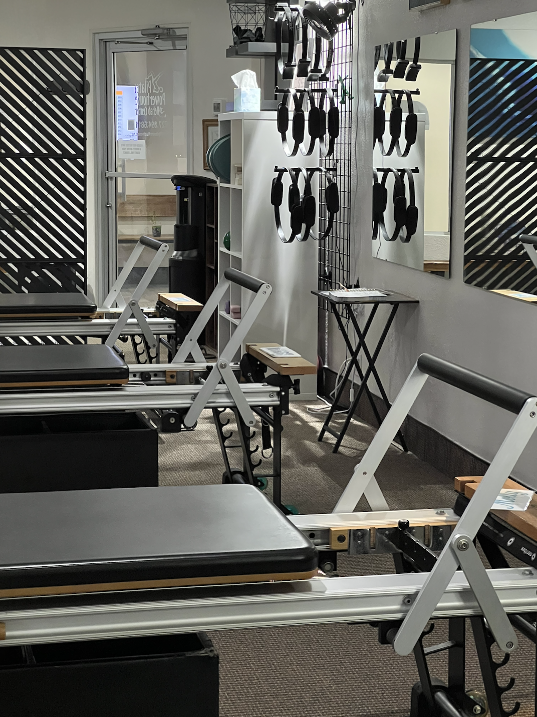 Empty physical therapy or rehabilitation exercise room with therapy tables, resistance bands, and mirrors.