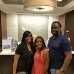 Three people standing in front of a check-in counter at a hotel, smiling.