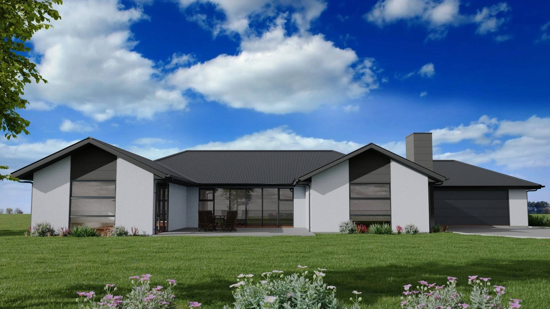 Modern single-story house with a dark gray roof, white walls, large windows, and a patio with outdoor furniture, surrounded by a green lawn and flowering plants, under a blue sky with clouds.