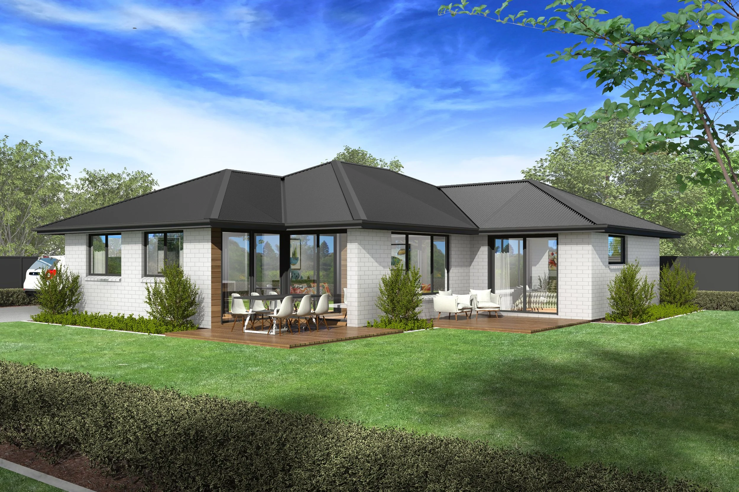 A modern single-story house with white brick walls, large glass windows and doors, surrounded by a grassy yard, shrubs, and trees, with an outdoor dining area on a wooden deck under a clear sky.