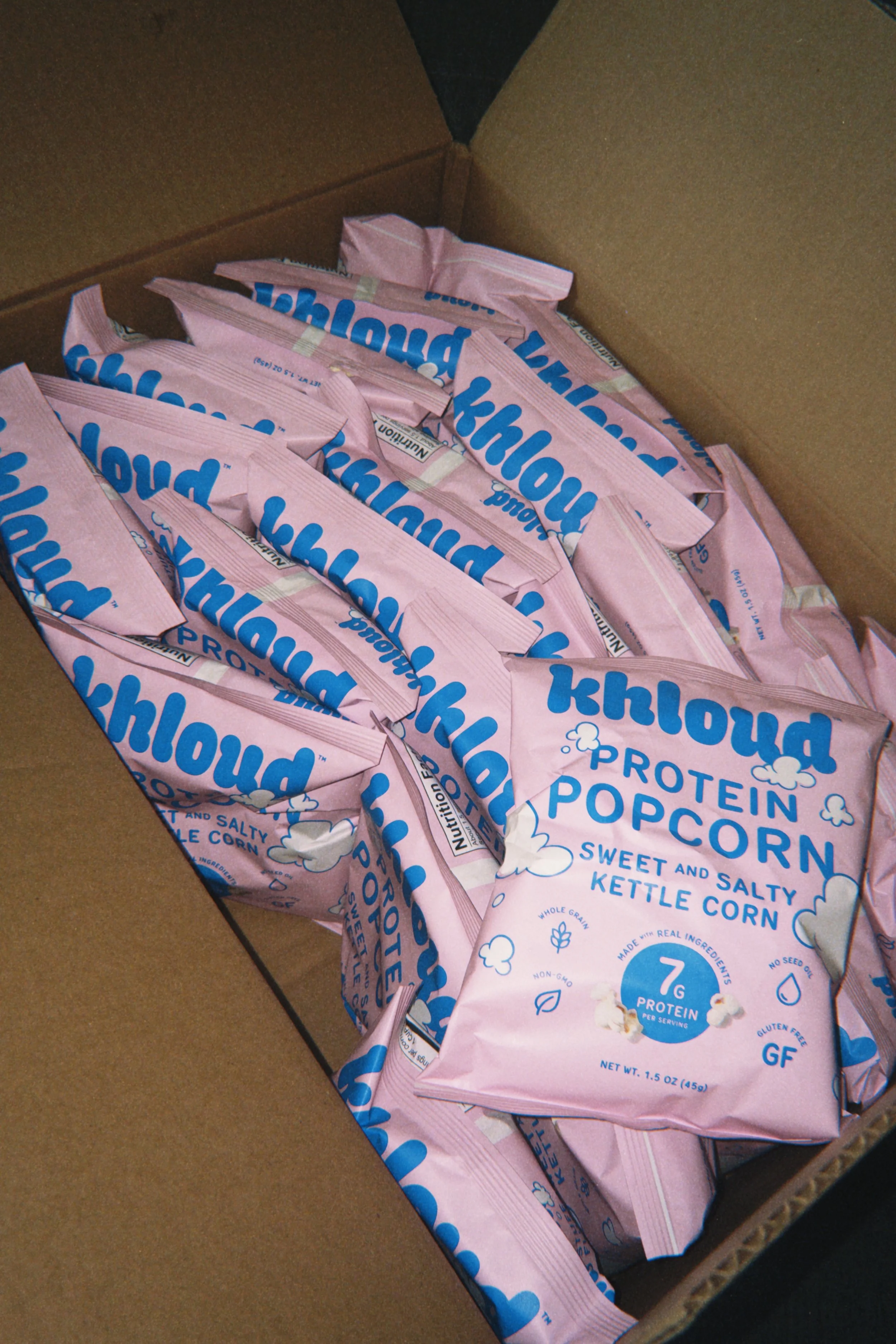 A cardboard box filled with pink bags of Kernel Season's sweet and salty kettle corn popcorn.