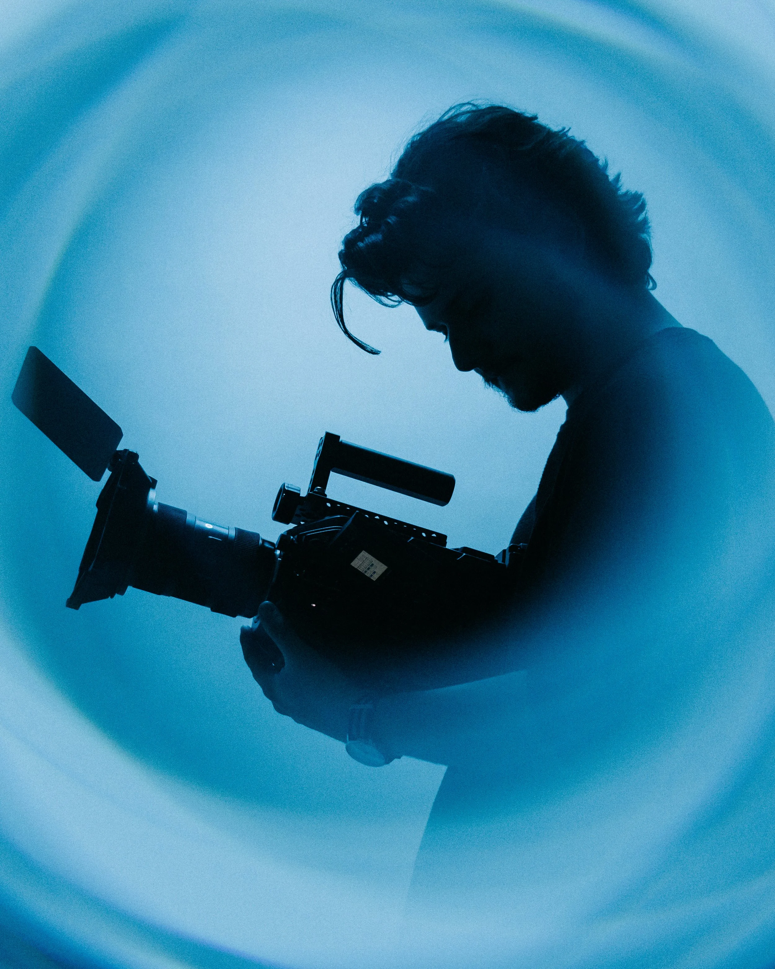 Silhouette of a scientist examining a sample through a microscope against a blue background.